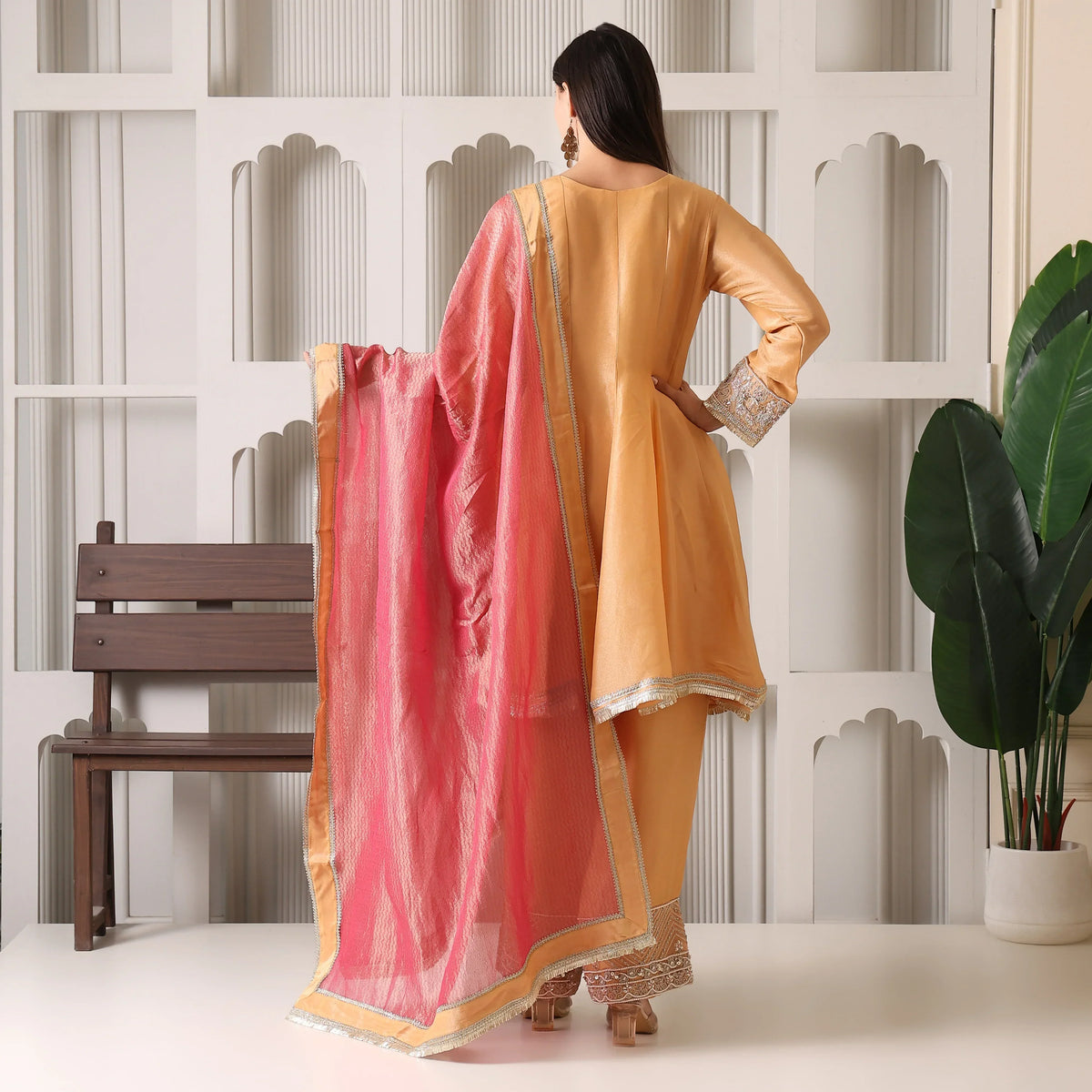 Woman in gold Anarkali suit with pink dupatta, luxury ethnic wear for festive occasions
