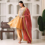 Woman in mustard yellow embroidered Anarkali suit with pink dupatta, festive ethnic wear