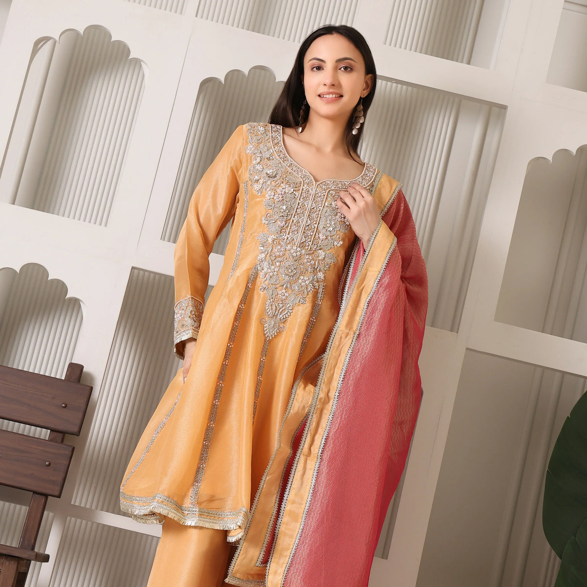 Woman wearing embellished yellow Anarkali suit with red dupatta, festive ethnic wear