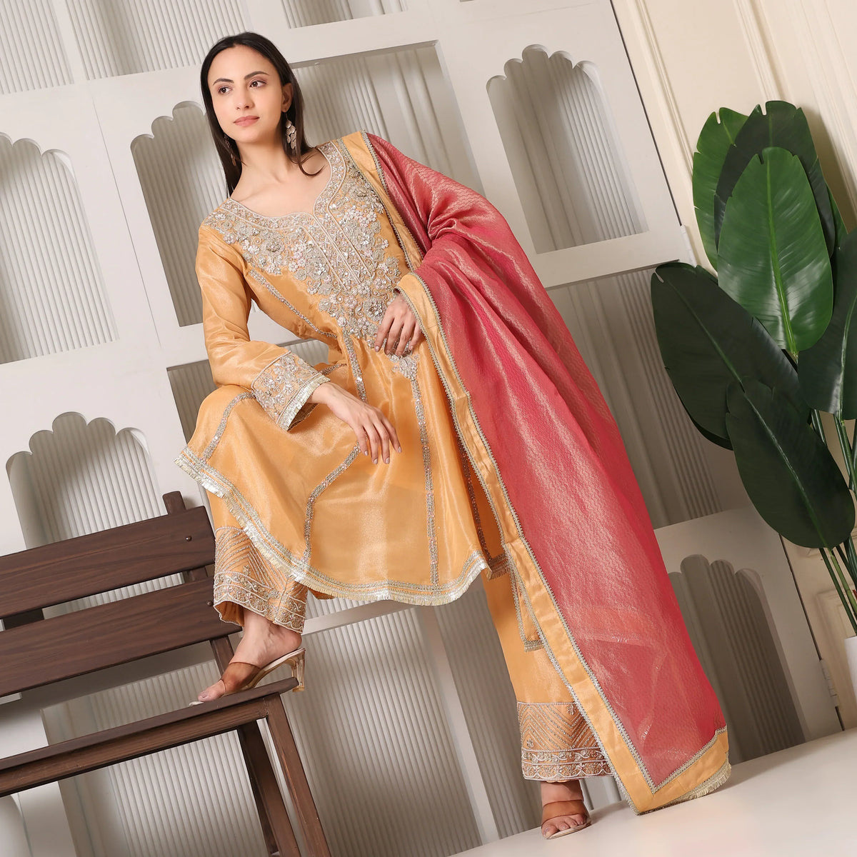 Woman wearing embellished yellow Anarkali suit with pink dupatta, ethnic festive outfit