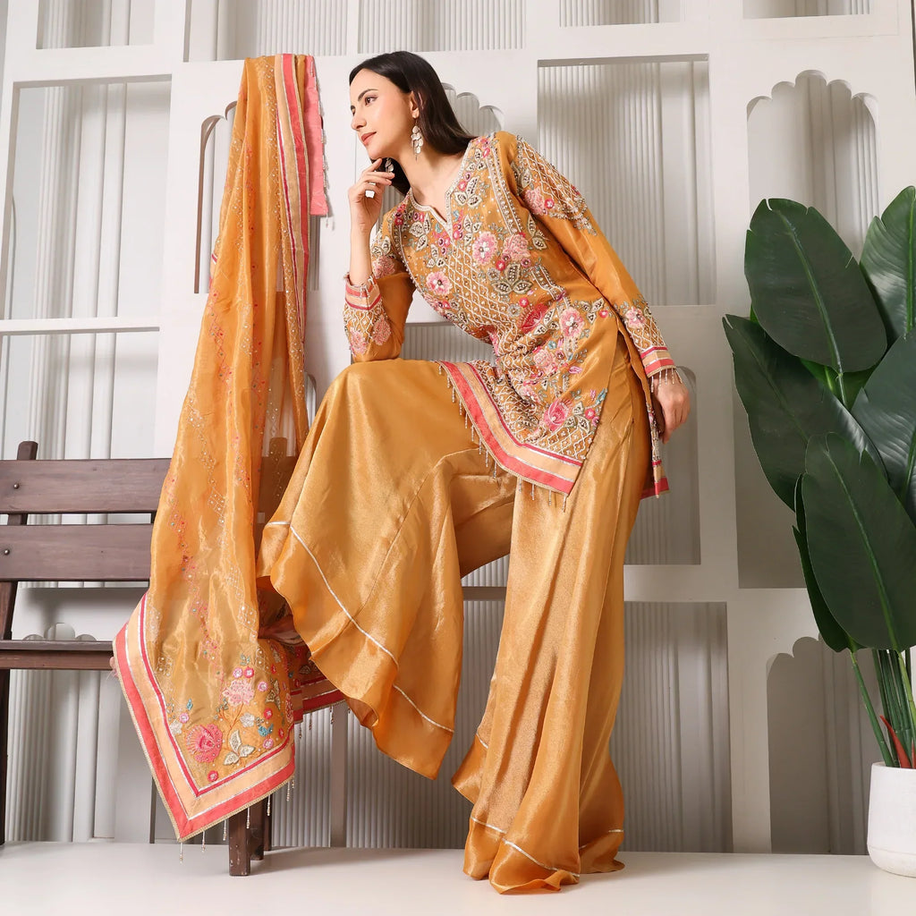Woman wearing a gold embroidered ethnic suit with wide-legged pants and dupatta, festive outfit