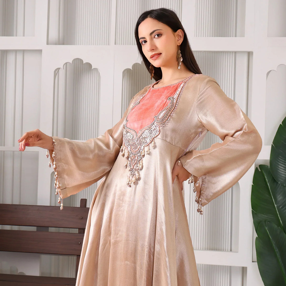 Woman wearing a beige silk Anarkali suit with peach embroidered yoke and flared sleeves