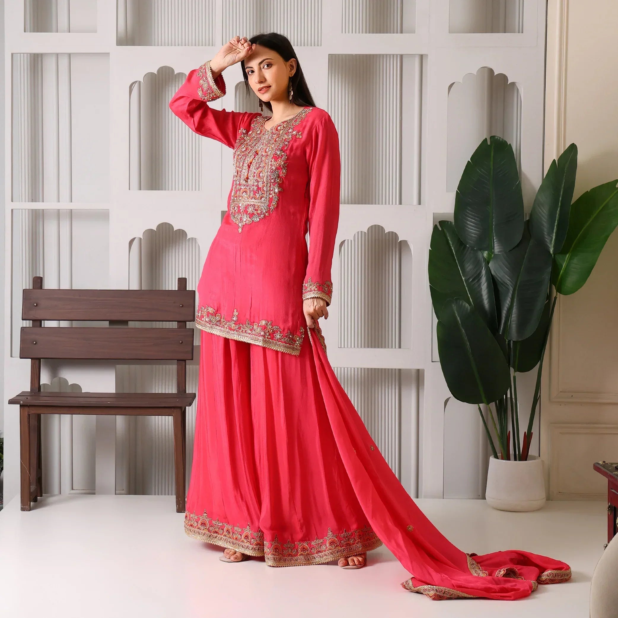 Woman in a pink embroidered ethnic suit with palazzo pants and dupatta, indoor setting