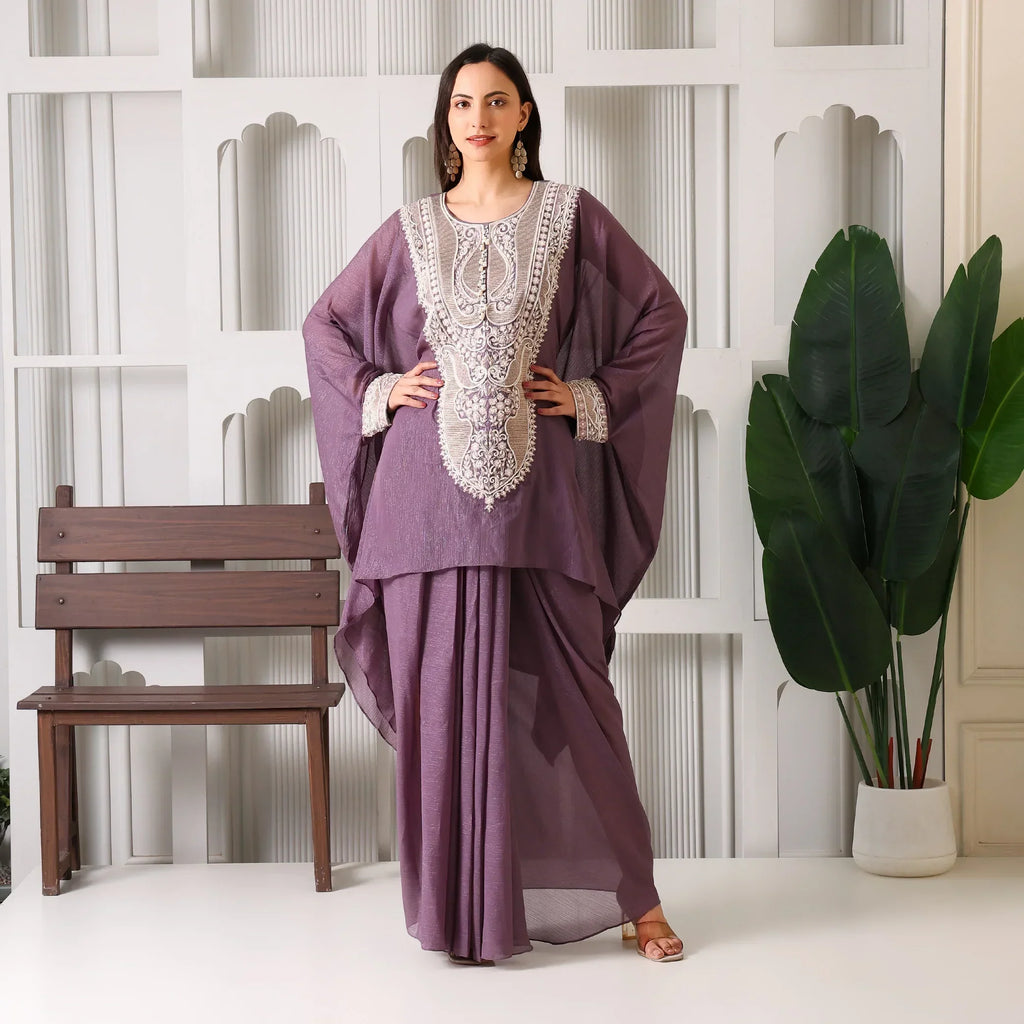 Woman wearing a mauve embroidered ethnic suit with wide sleeves, standing indoors