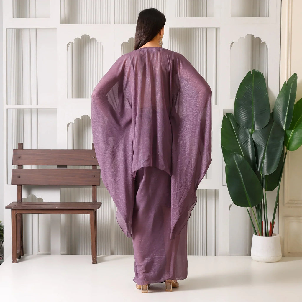 Woman in mauve ethnic designer outfit with flowy sleeves, standing indoors