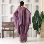 Woman in mauve ethnic designer outfit with flowy sleeves, standing indoors