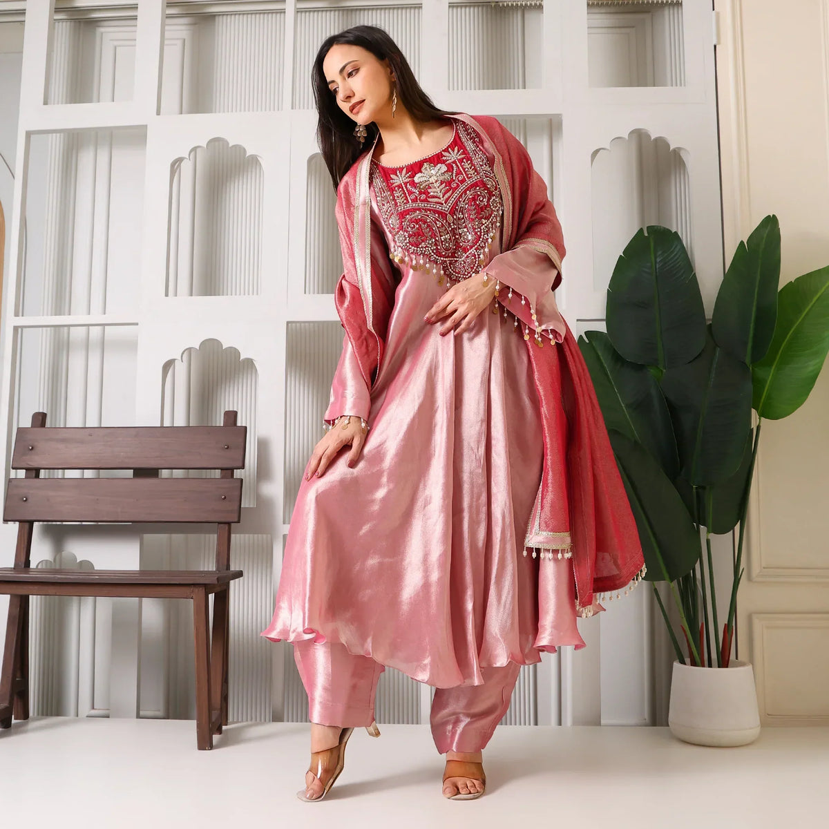 Woman wearing pink Banarasi Anarkali suit set with dupatta, posing indoors
