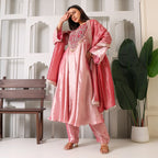 Woman wearing pink Banarasi Anarkali suit with dupatta and detailed embroidery, festive setting