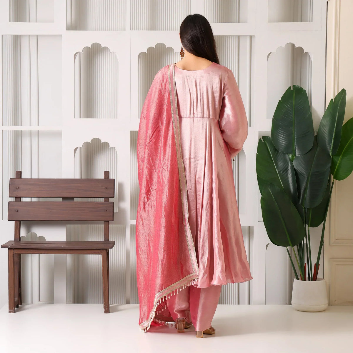 Woman in a pink Banarasi Anarkali suit with dupatta, back view, indoor setting