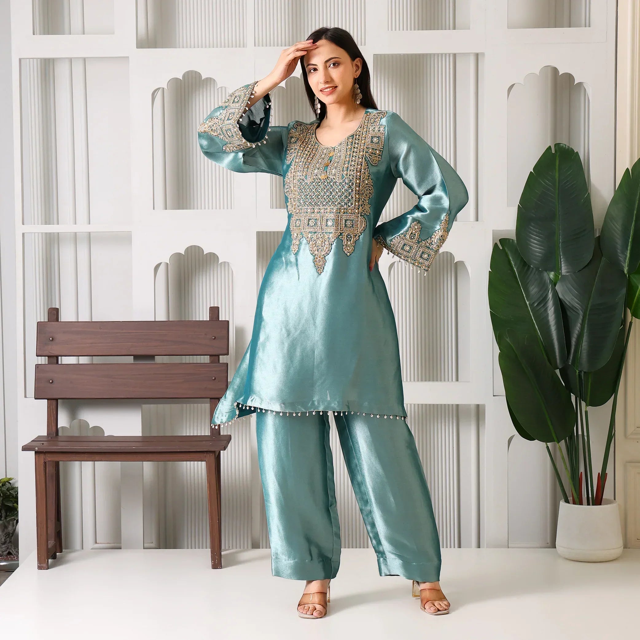 Woman wearing teal embroidered ethnic kurta set with wide pants, standing indoors