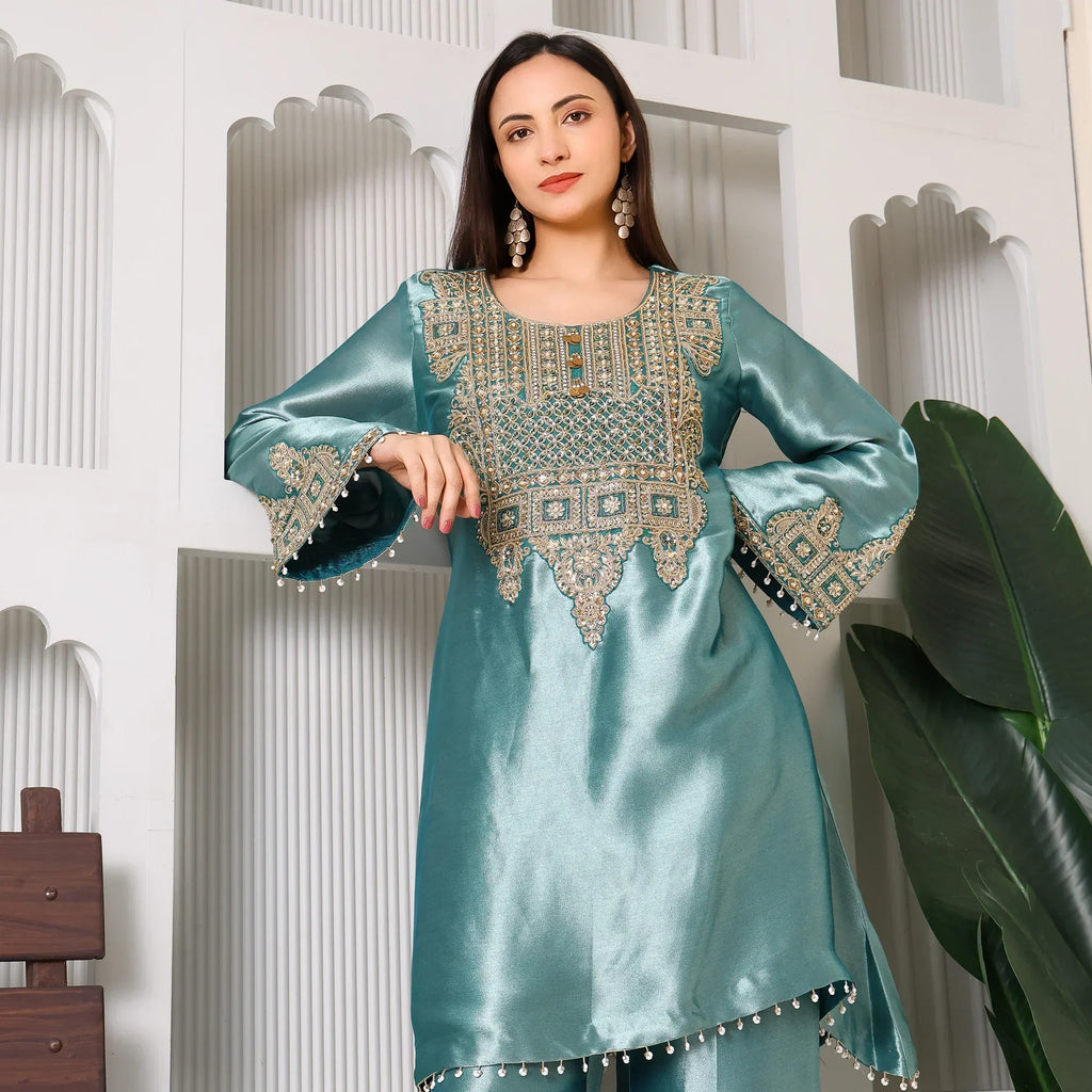 Woman in teal silk kurta with intricate gold embroidery, wearing statement earrings