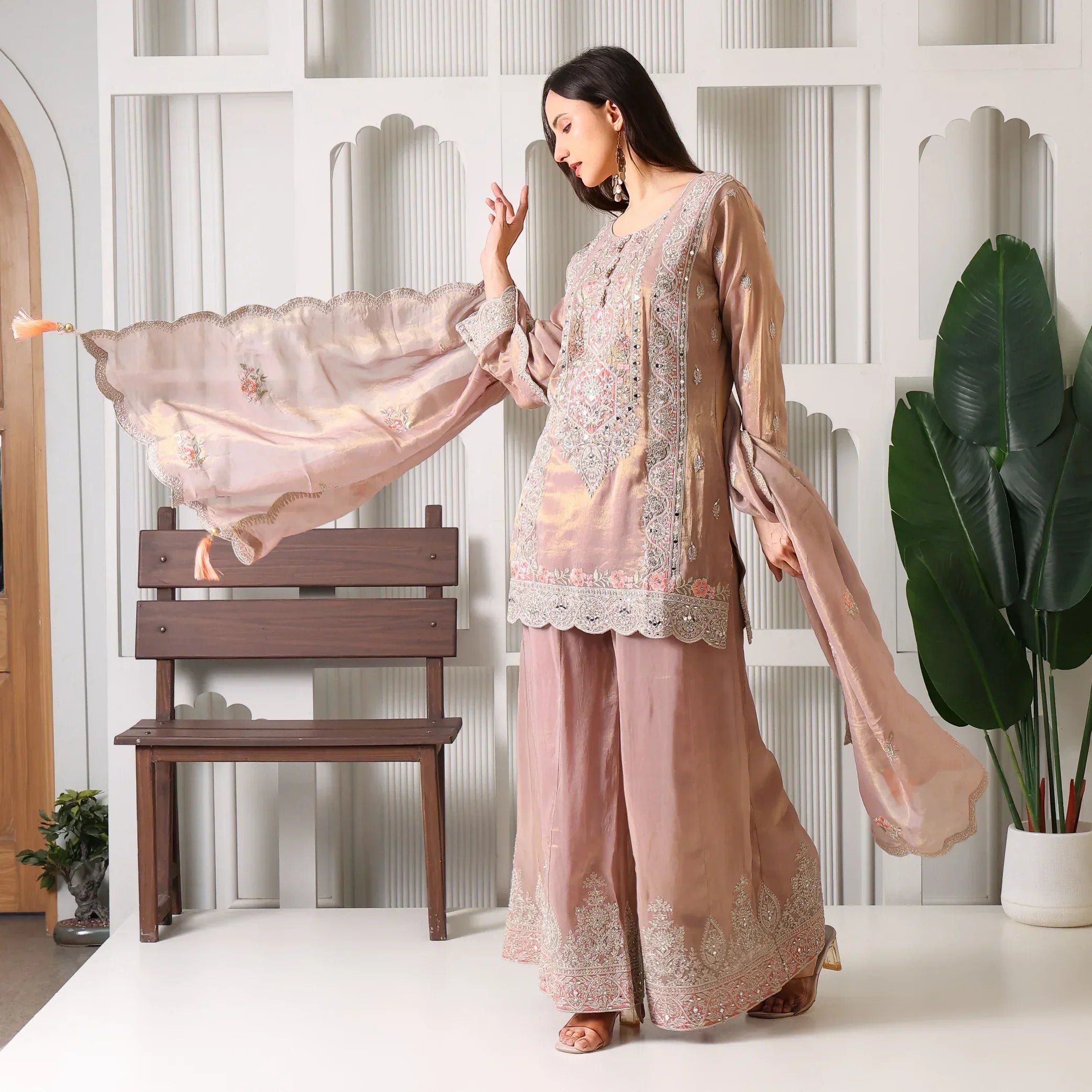 Woman wearing embroidered mauve ethnic suit with palazzo pants and dupatta, indoors