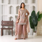 Woman in blush pink embroidered ethnic palazzo suit with dupatta, standing indoors