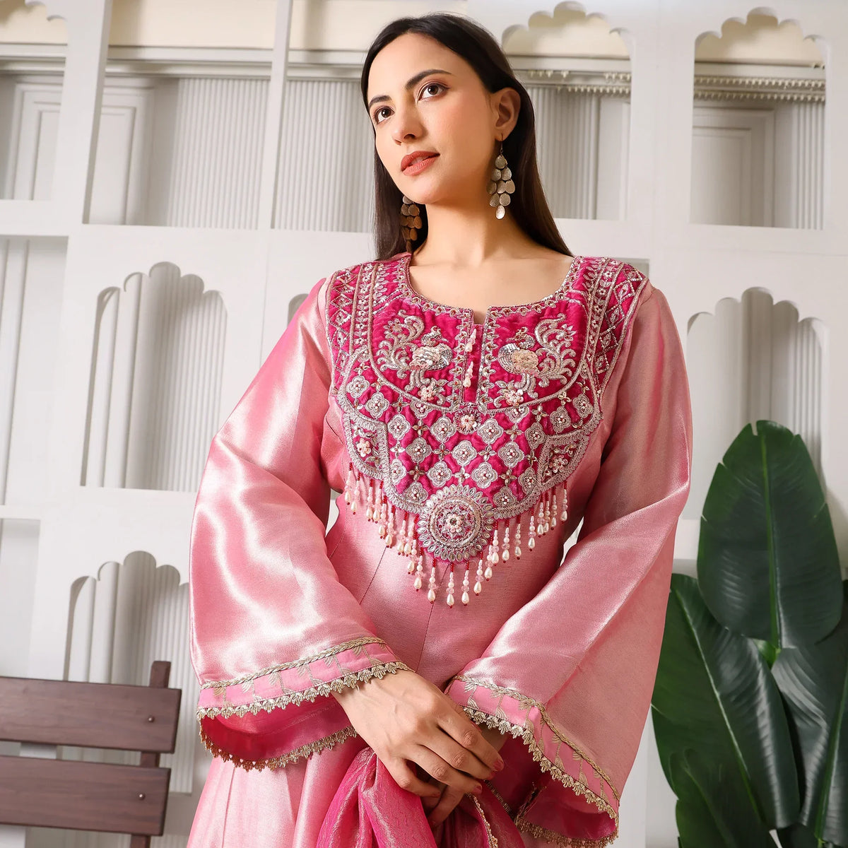 Woman in pink embroidered Banarasi Anarkali suit with statement earrings, festive setting