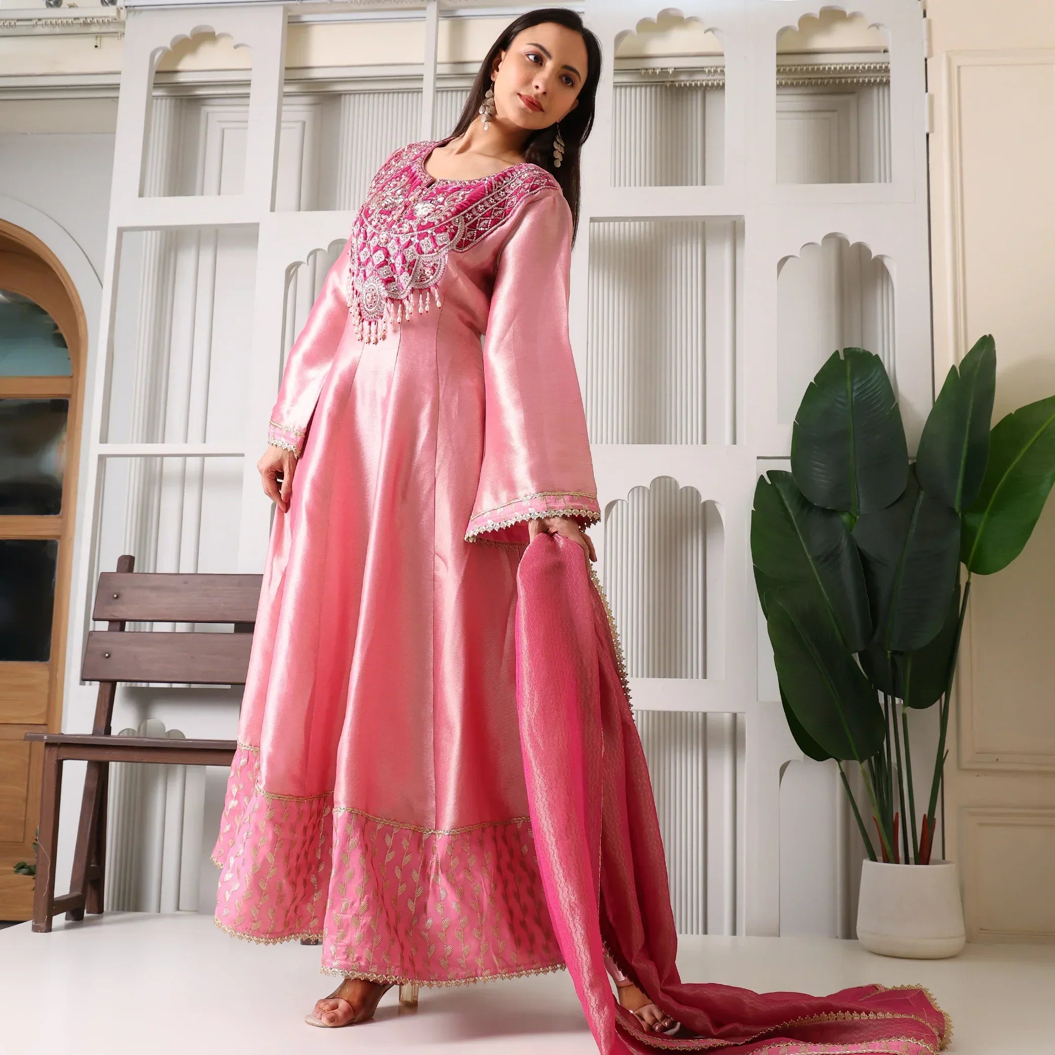 Woman wearing pink Banarasi Anarkali suit with embroidered yoke, holding matching dupatta