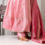 Pink Banarasi Anarkali suit with gold embroidery and matching dupatta, worn with heels