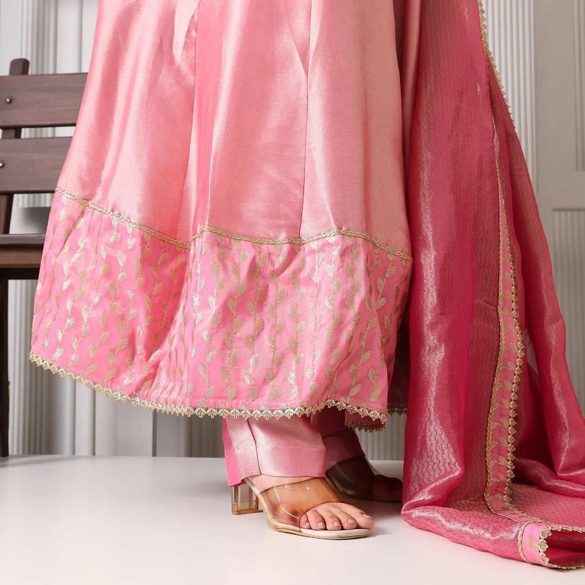 Pink Banarasi Anarkali suit with gold embroidery and matching dupatta, worn with heels