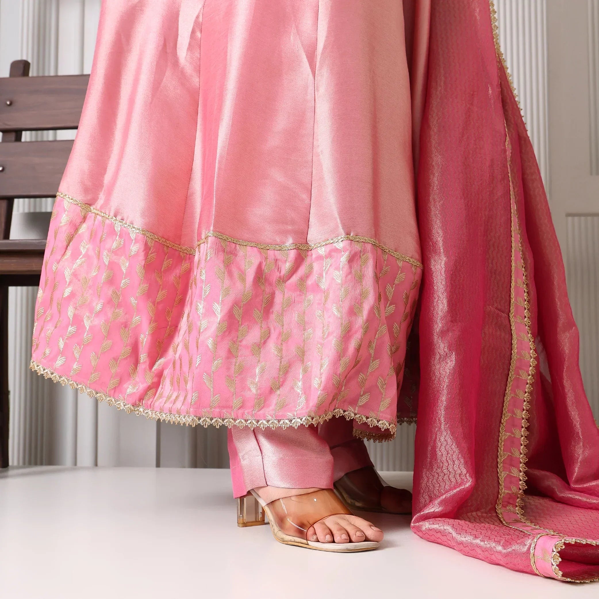 Pink Banarasi Anarkali suit with gold embroidery and matching dupatta, worn with heels