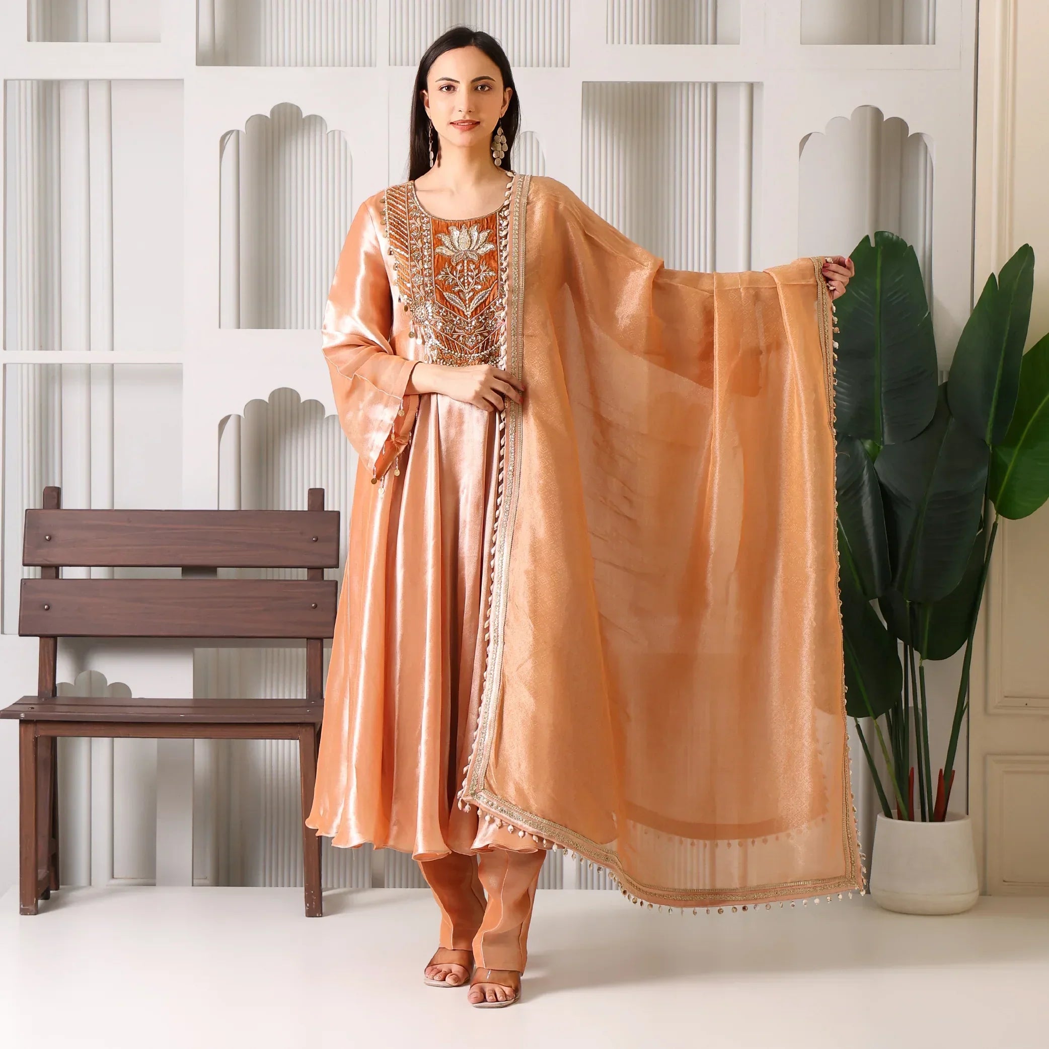 Woman wearing peach Banarasi Anarkali suit with dupatta, standing indoors
