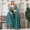Woman in teal Banarasi embroidered ethnic three-piece set with dupatta, posing indoors