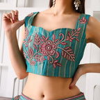 Woman wearing teal ethnic crop top with pink floral embroidery and striped detailing