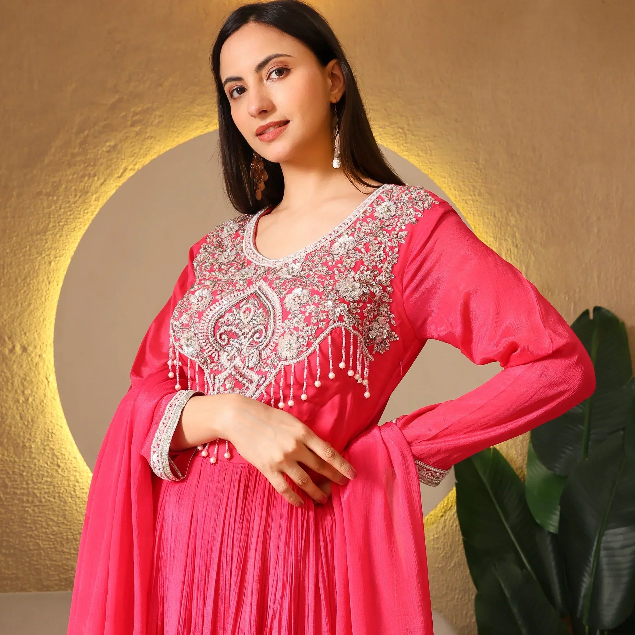 Woman wearing a pink Anarkali suit with intricate silver embroidery and beadwork detailing