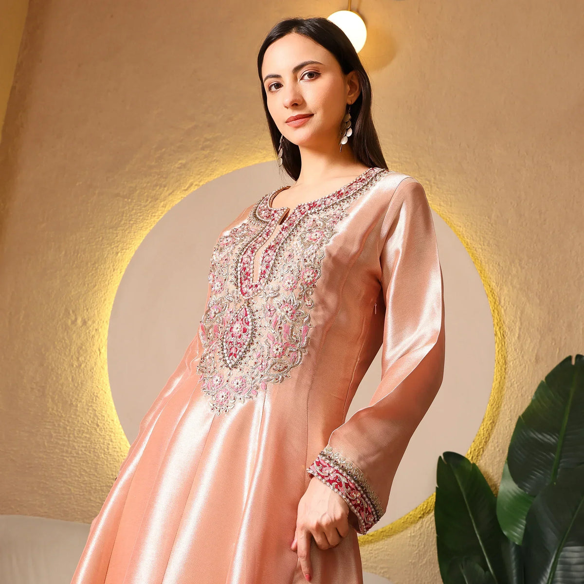 Woman in peach silk Anarkali suit with intricate bead embroidery, elegant ethnic wear