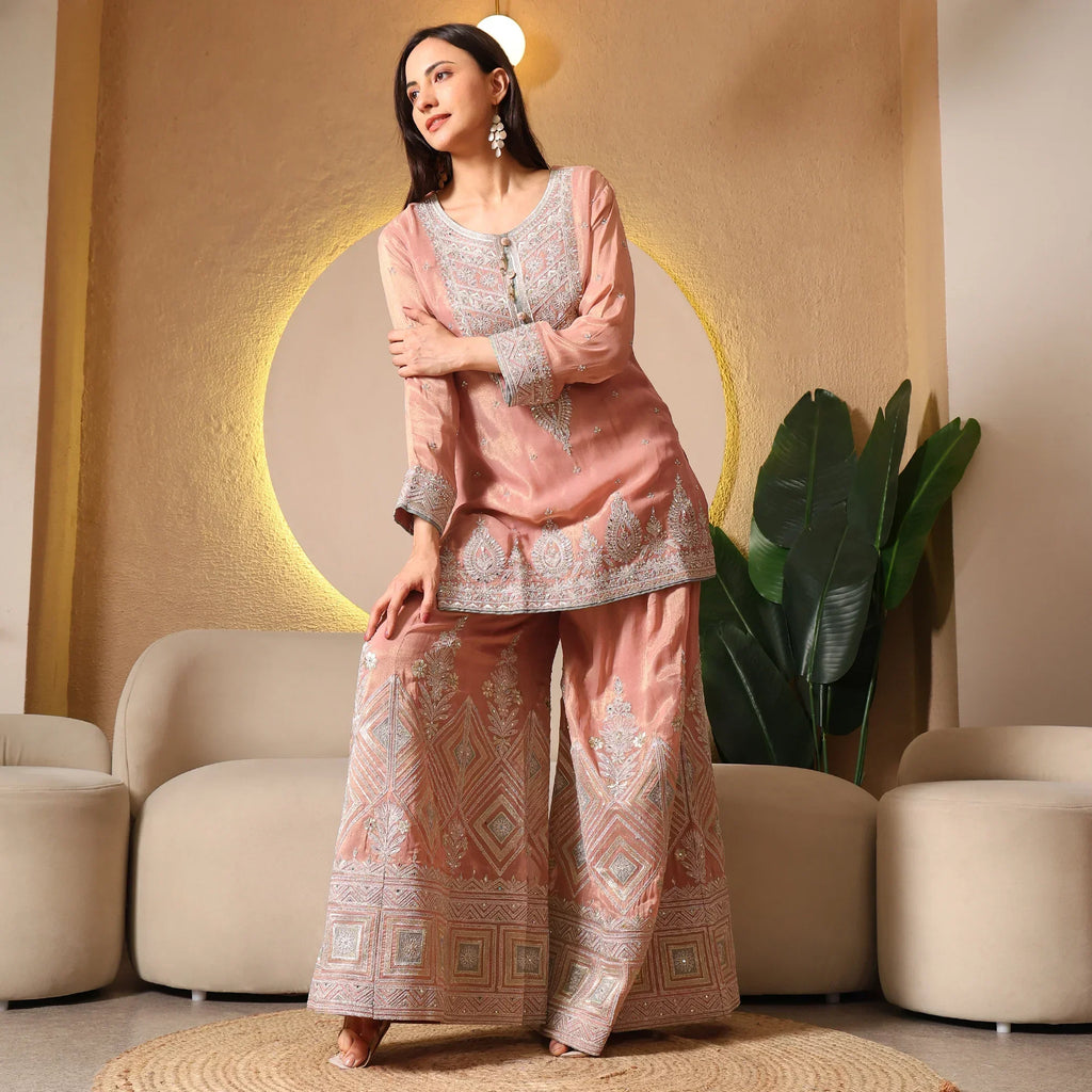 Woman wearing peach ethnic embroidered kurta and wide-leg pants set in modern living room