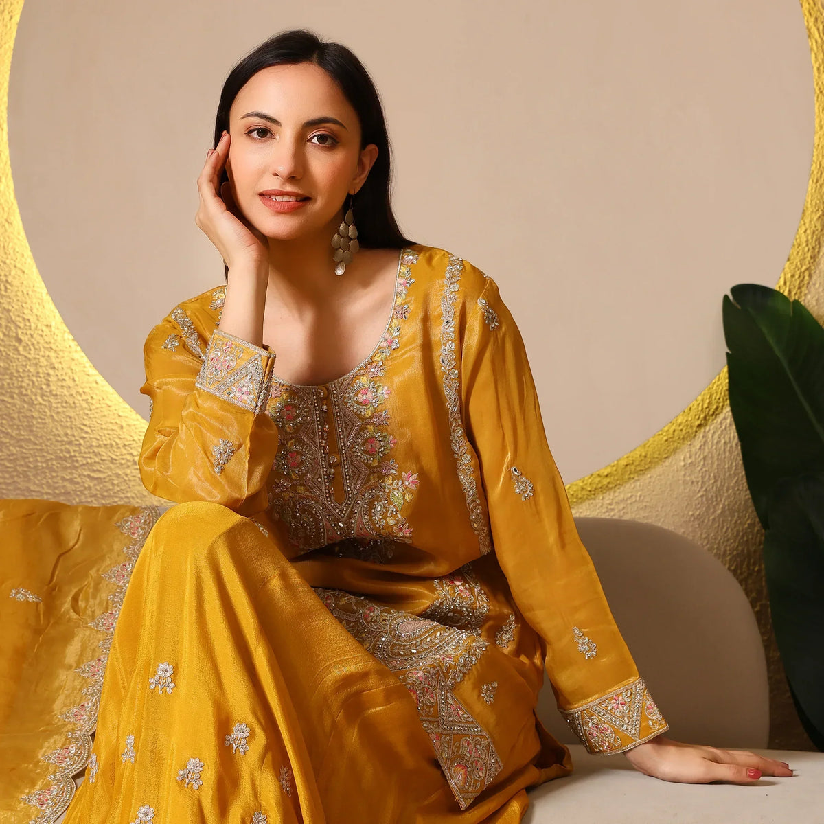 Woman in mustard embroidered ethnic suit with dupatta, sitting indoors, festive look
