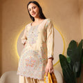 Woman in cream embroidered ethnic kurta set with pastel floral patterns, holding yellow dupatta
