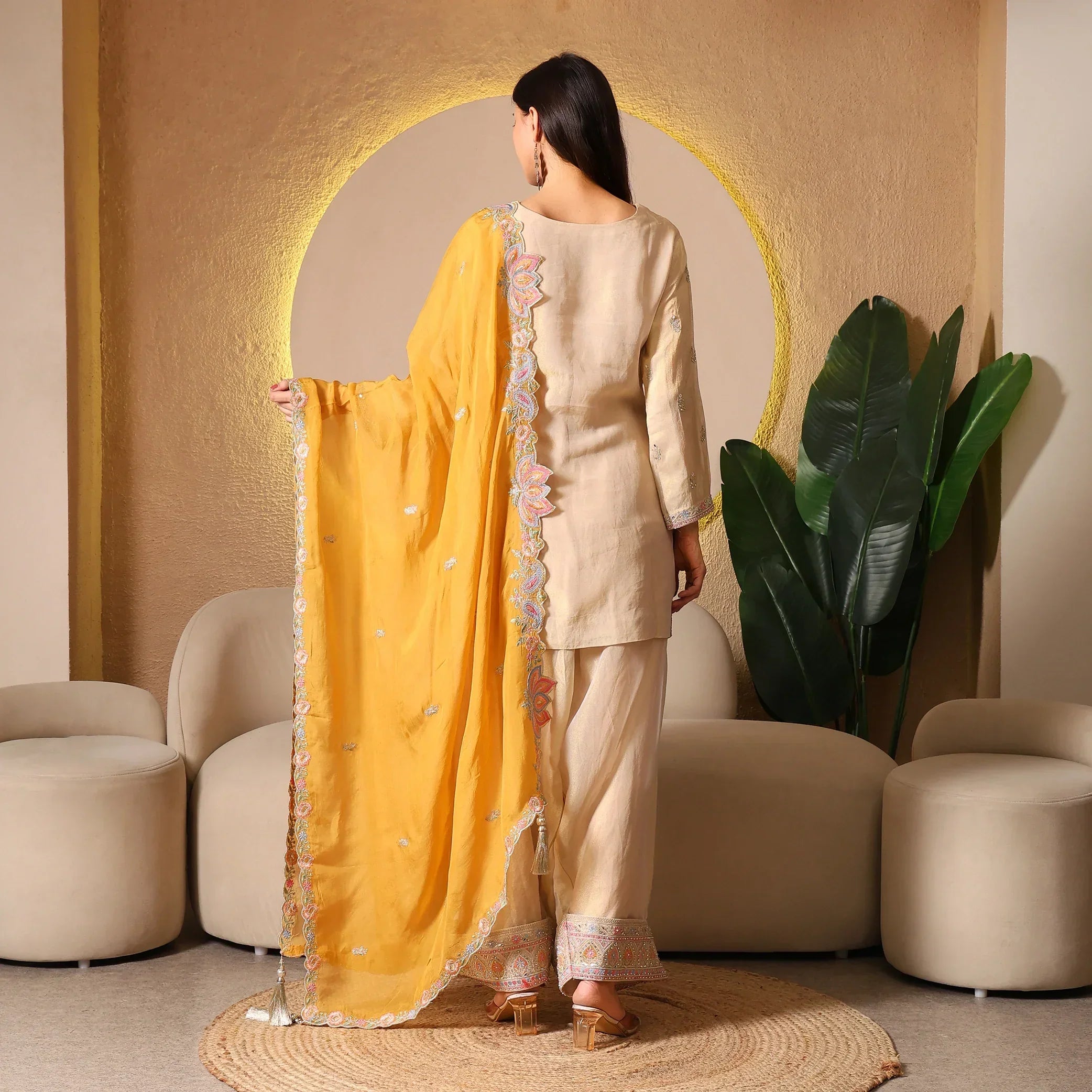 Woman in beige ethnic suit with embroidered yellow dupatta, luxury festive wear