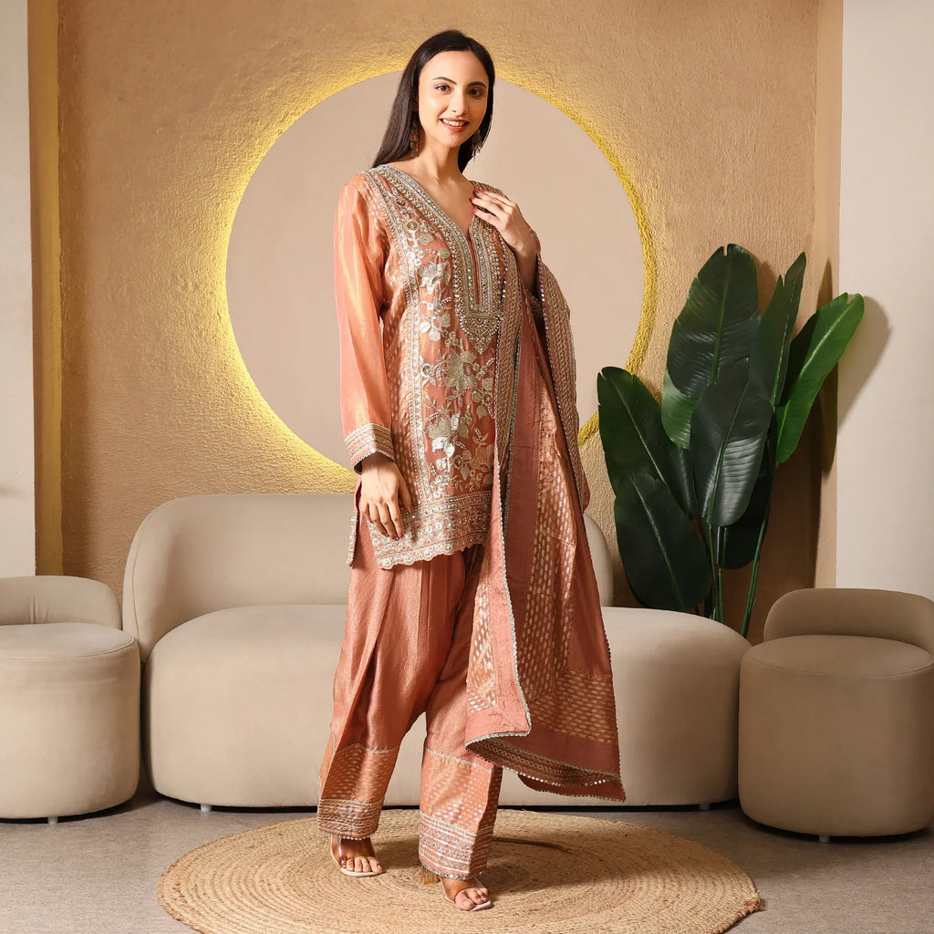 Woman wearing an embroidered ethnic suit with dupatta in a modern living room setting
