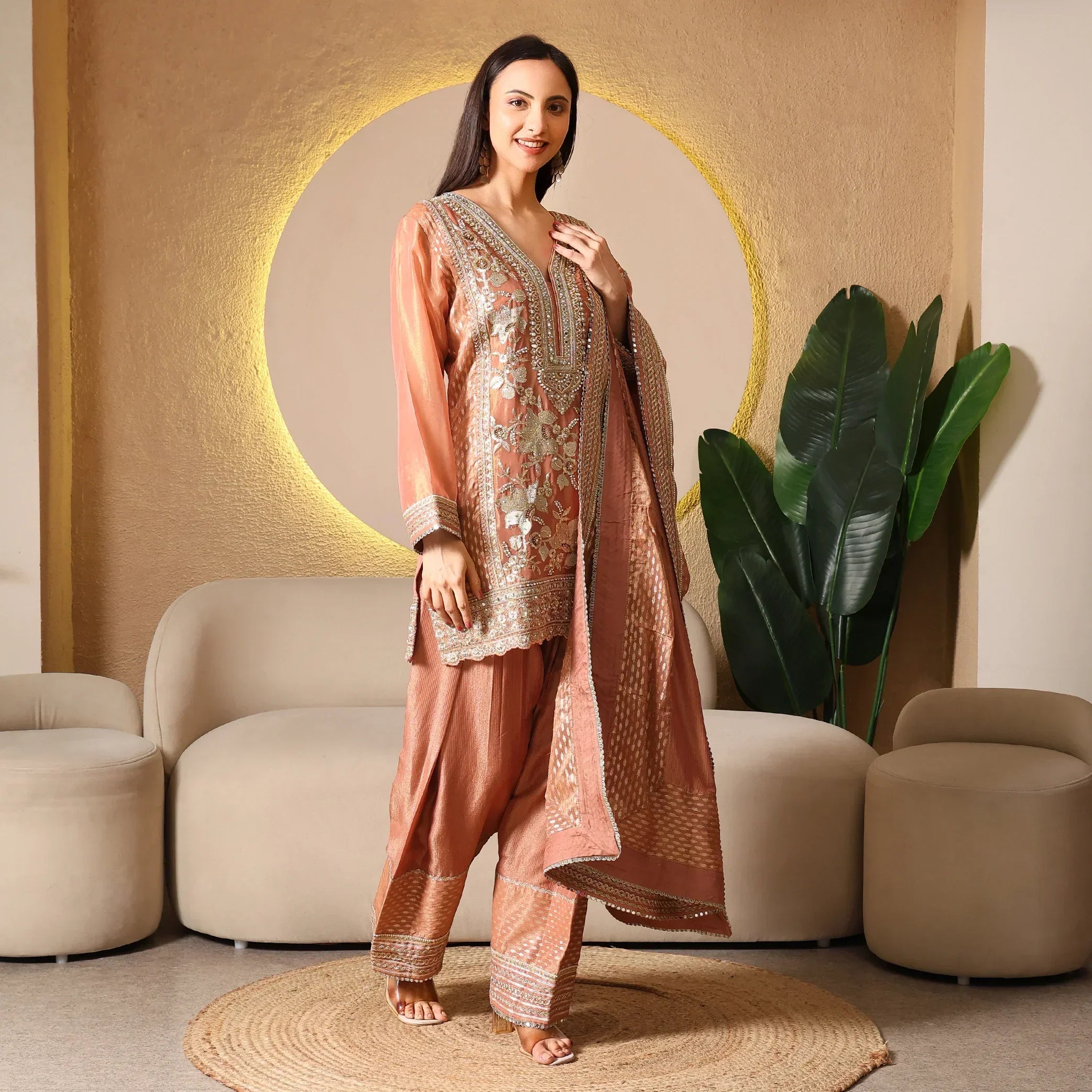 Woman wearing an embroidered ethnic suit with dupatta in a modern living room setting