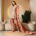 Woman modeling an embroidered peach ethnic suit with dupatta, seated indoor setting