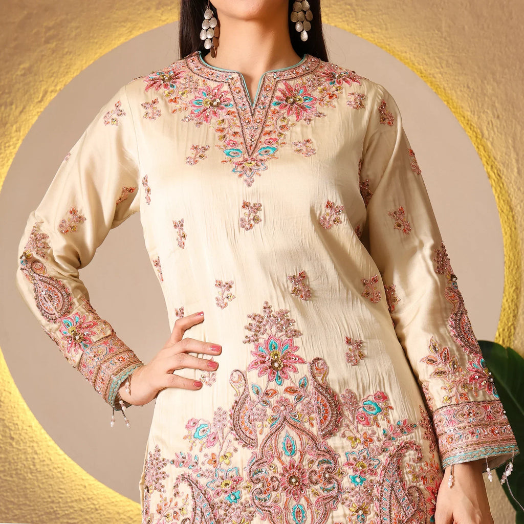 Woman wearing cream embroidered Anarkali suit with floral patterns and statement earrings