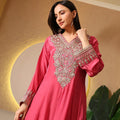 Woman wearing a pink Banarasi Anarkali suit with intricate gold embroidery, festive setting