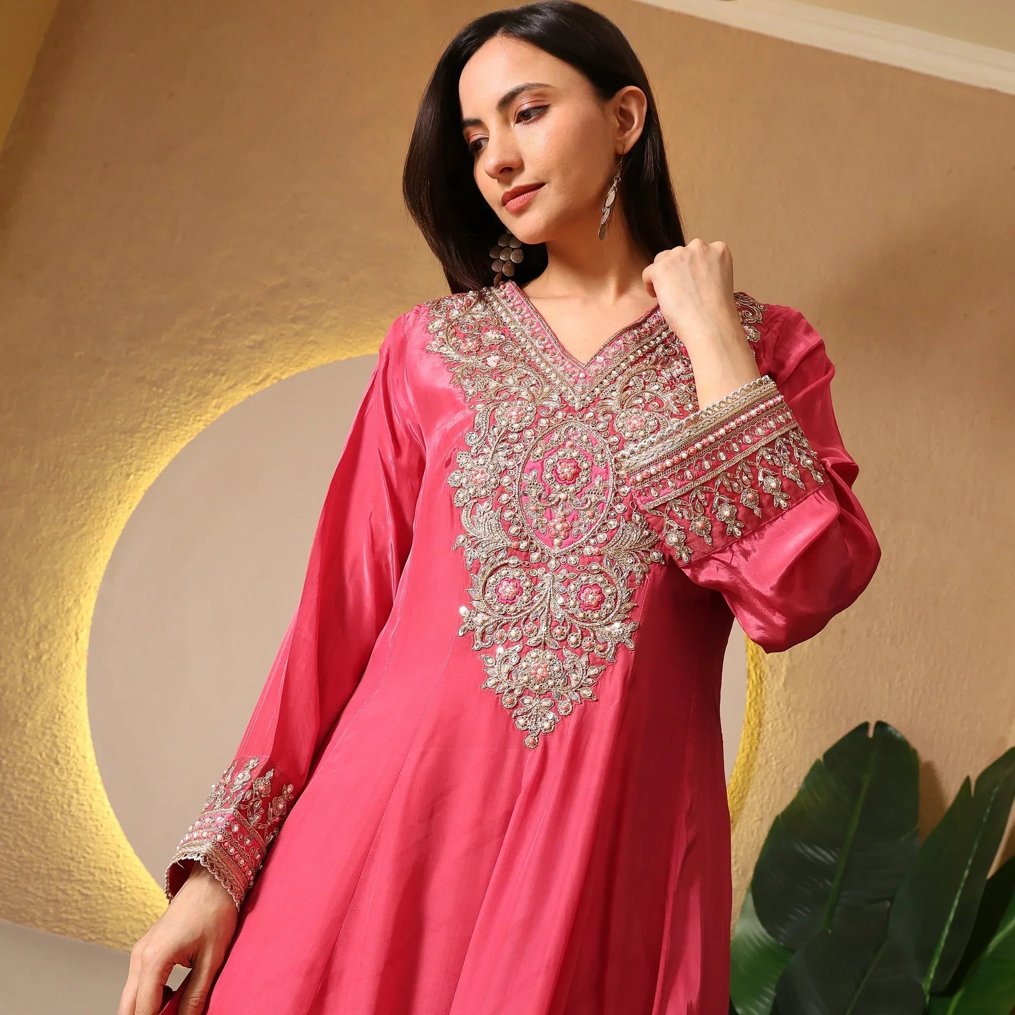 Woman wearing a pink Banarasi Anarkali suit with intricate gold embroidery, festive setting