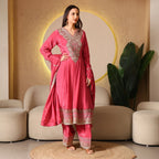 Woman wearing a pink Banarasi Anarkali suit with intricate embroidery, standing indoors