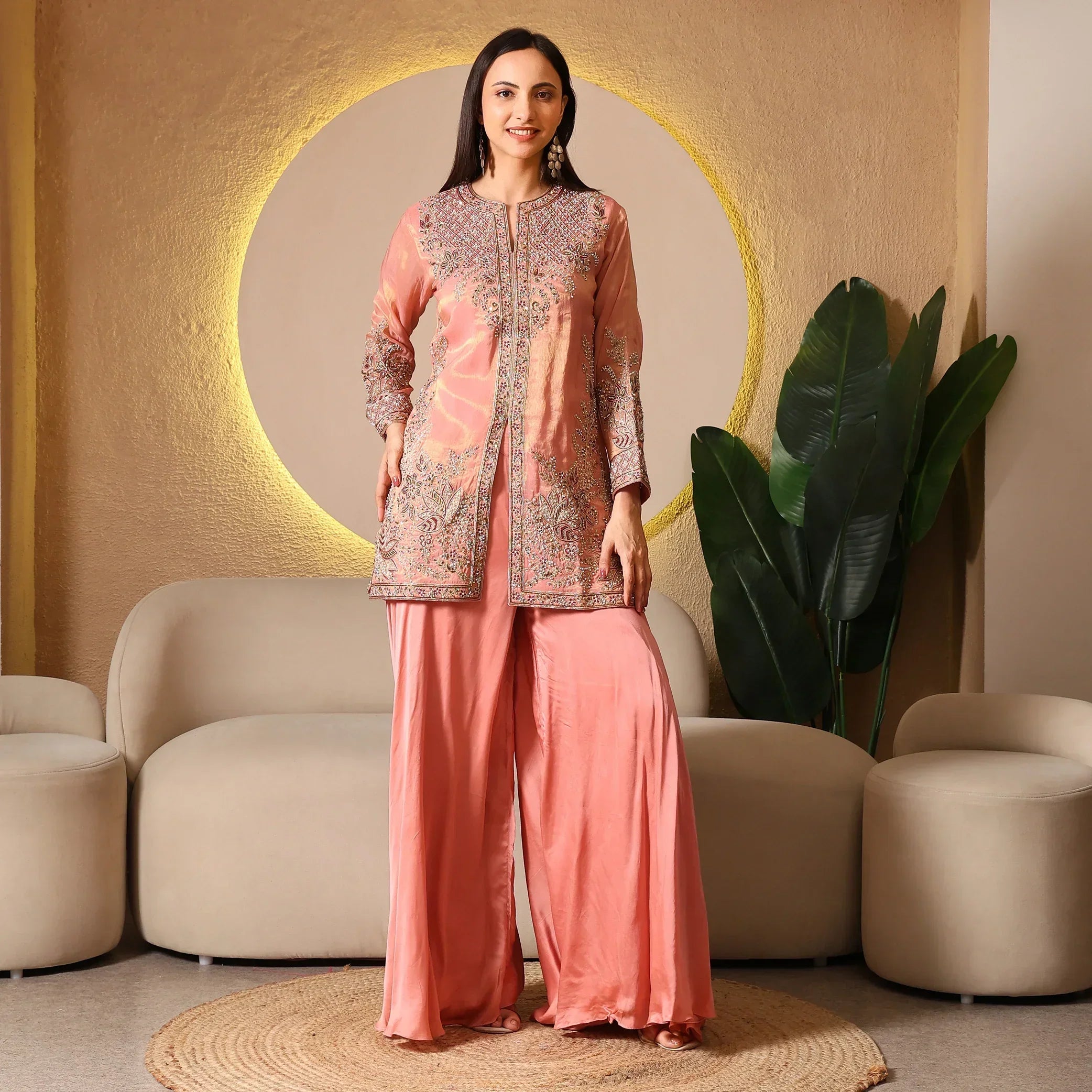 Woman wearing a peach embroidered ethnic suit with wide-leg pants, standing indoors
