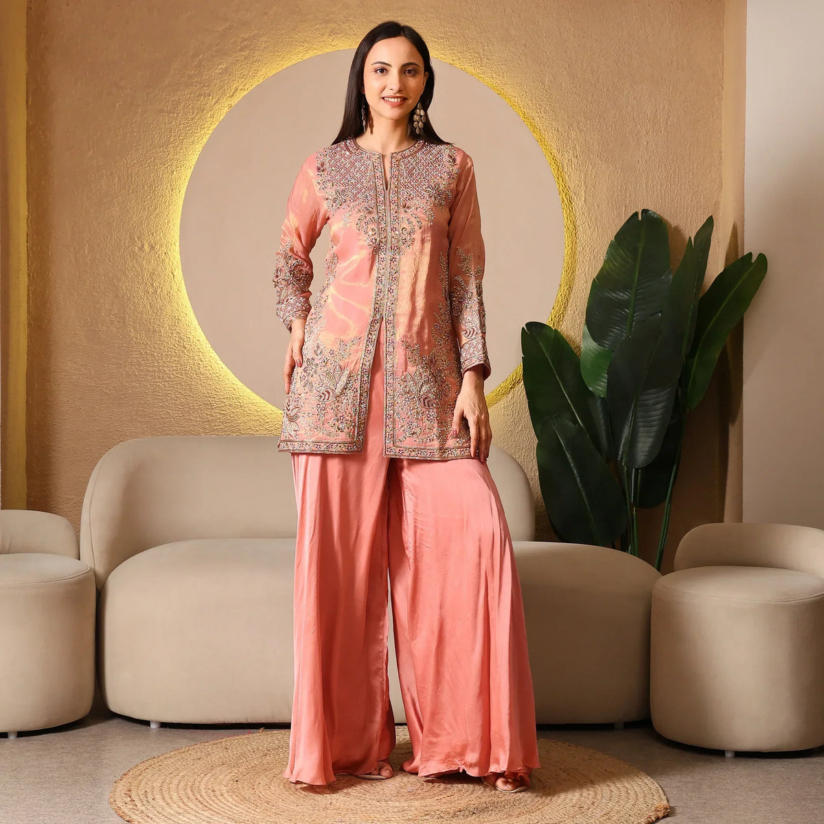 Woman wearing a peach embroidered ethnic suit with wide-leg pants, standing indoors