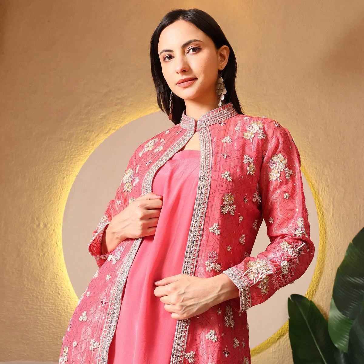 Woman wearing pink embroidered ethnic jacket with floral motifs, festive outfit indoors