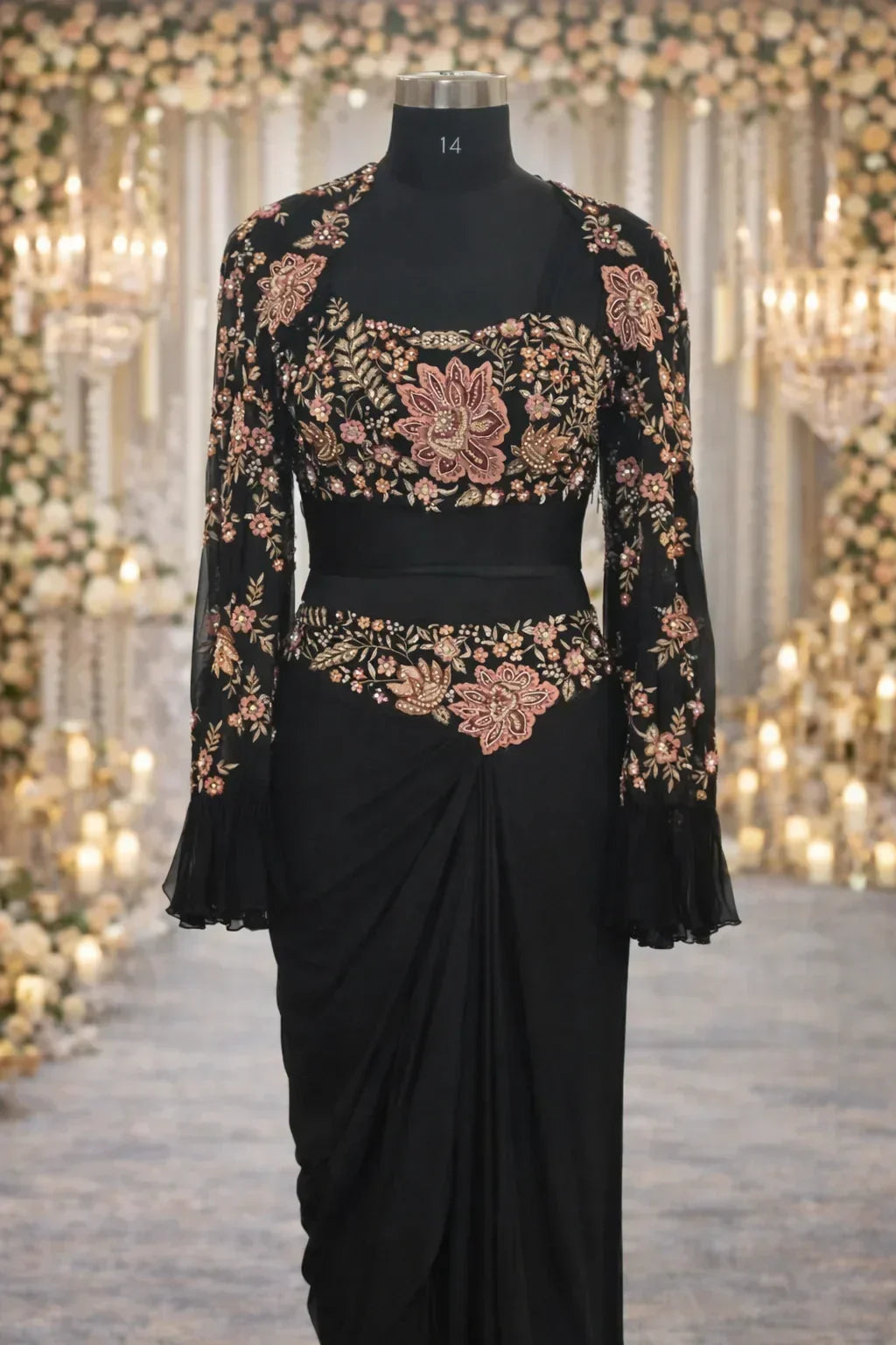 Black designer saree gown with pink floral embroidery, full sleeves, and draped skirt on mannequin