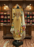 Gold embroidered ethnic suit with floral dupatta on mannequin in luxury boutique setting