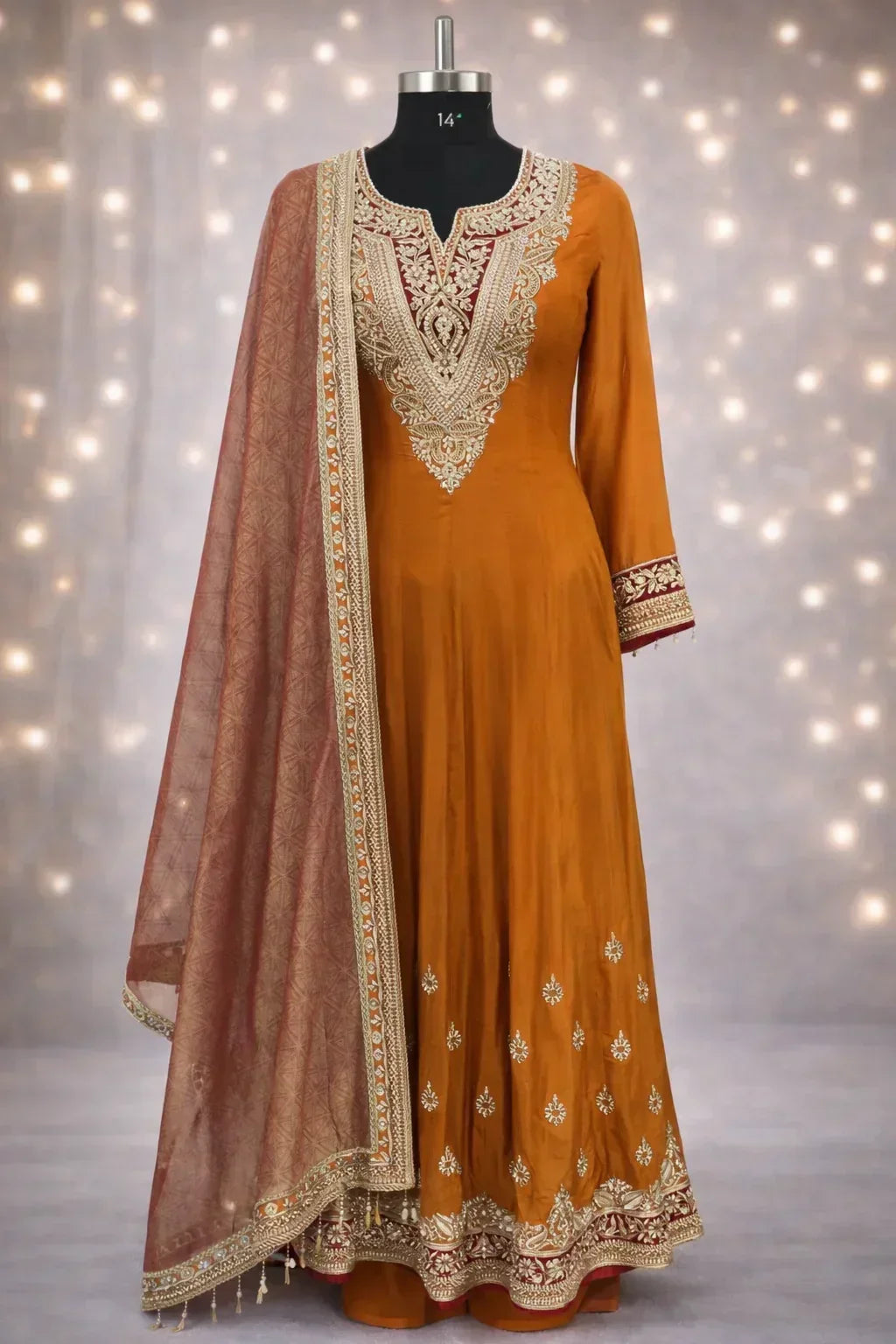 Embroidered mustard Anarkali suit with ornate dupatta on mannequin, festive ethnic wear