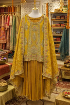 Yellow Banarasi Anarkali suit with embroidered dupatta and pleated skirt on mannequin in boutique