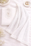 Flatlay of elegant white ethnic suit fabric with lace dupatta, pearls and gold bangles