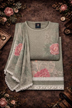 Folded pastel green ethnic suit set with pink floral embroidery and lace border, displayed flat.