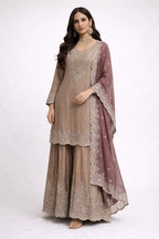 Woman wearing a beige embroidered Anarkali suit with dupatta, ideal for weddings or festive occasions