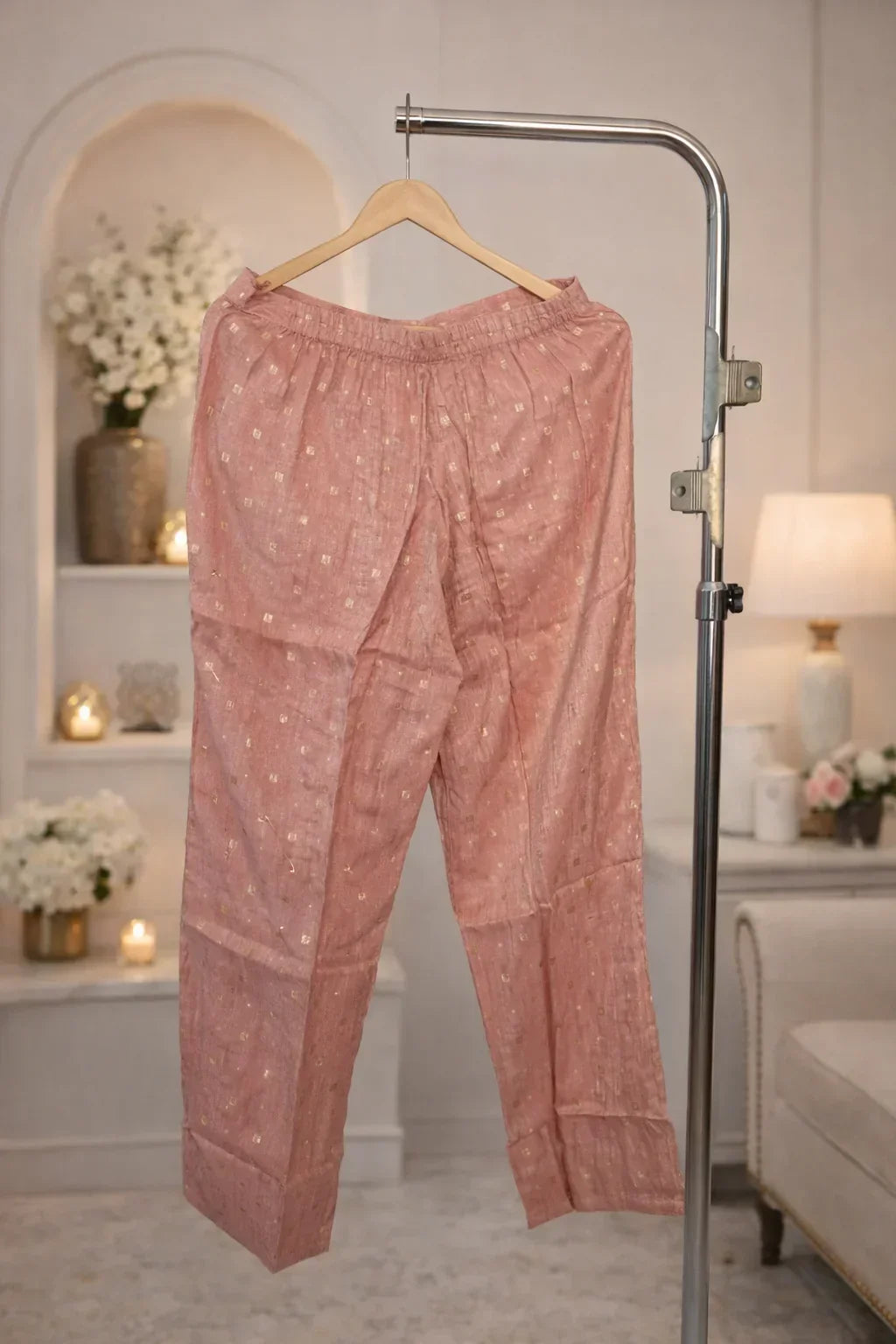 Dusty pink ethnic pants with gold detailing, displayed on hanger in elegant room setting