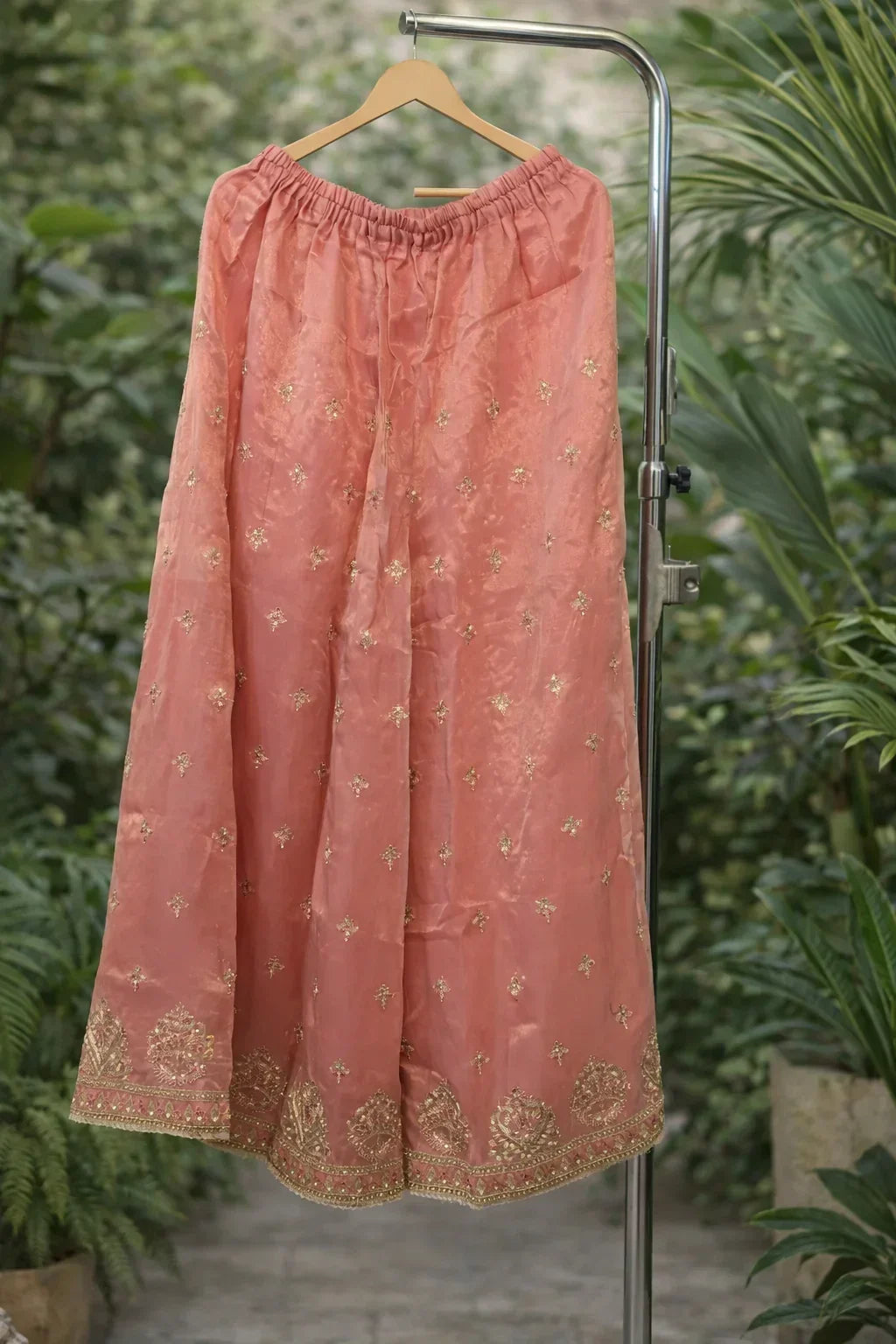 Peach ethnic skirt with gold embroidery and border, displayed on hanger outdoors